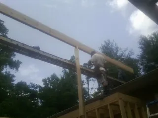 Carpenter setting a ridge beam over a new addition frame — Ice Dam Removal by Roofing Brothers in Montrose